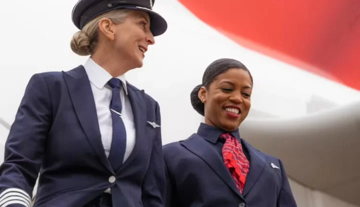 Two women in uniform stand proudly beside an airplane, showcasing their dedication and professionalism in aviation.
